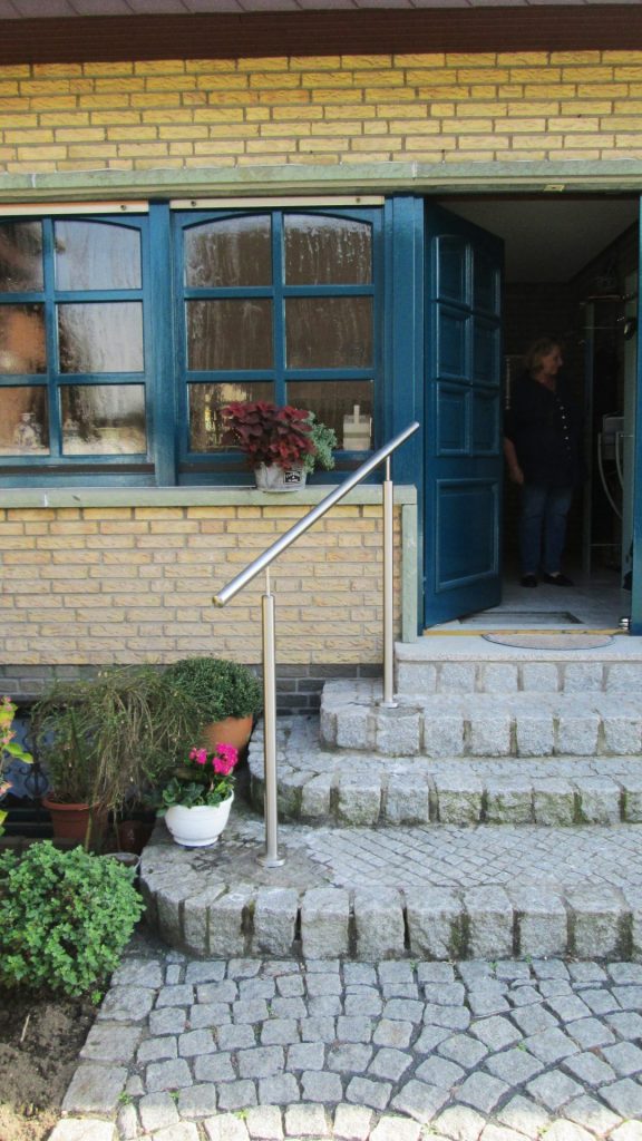 Gerader, robuster Edelstahlhandlauf an Steintreppe zum Hauseingang – barrierefreier Zugang.