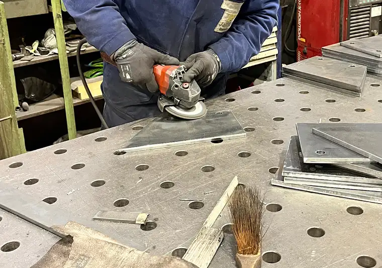 Metallbauhelfer bei Janßen beim Bearbeiten von Stahlbauteilen in der Werkstatt