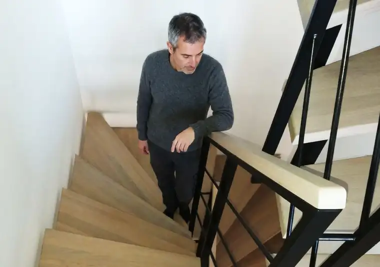 Ein Mann steht auf einer modernen Zweiholmtreppe und begutachtet die Linienführung der Treppe