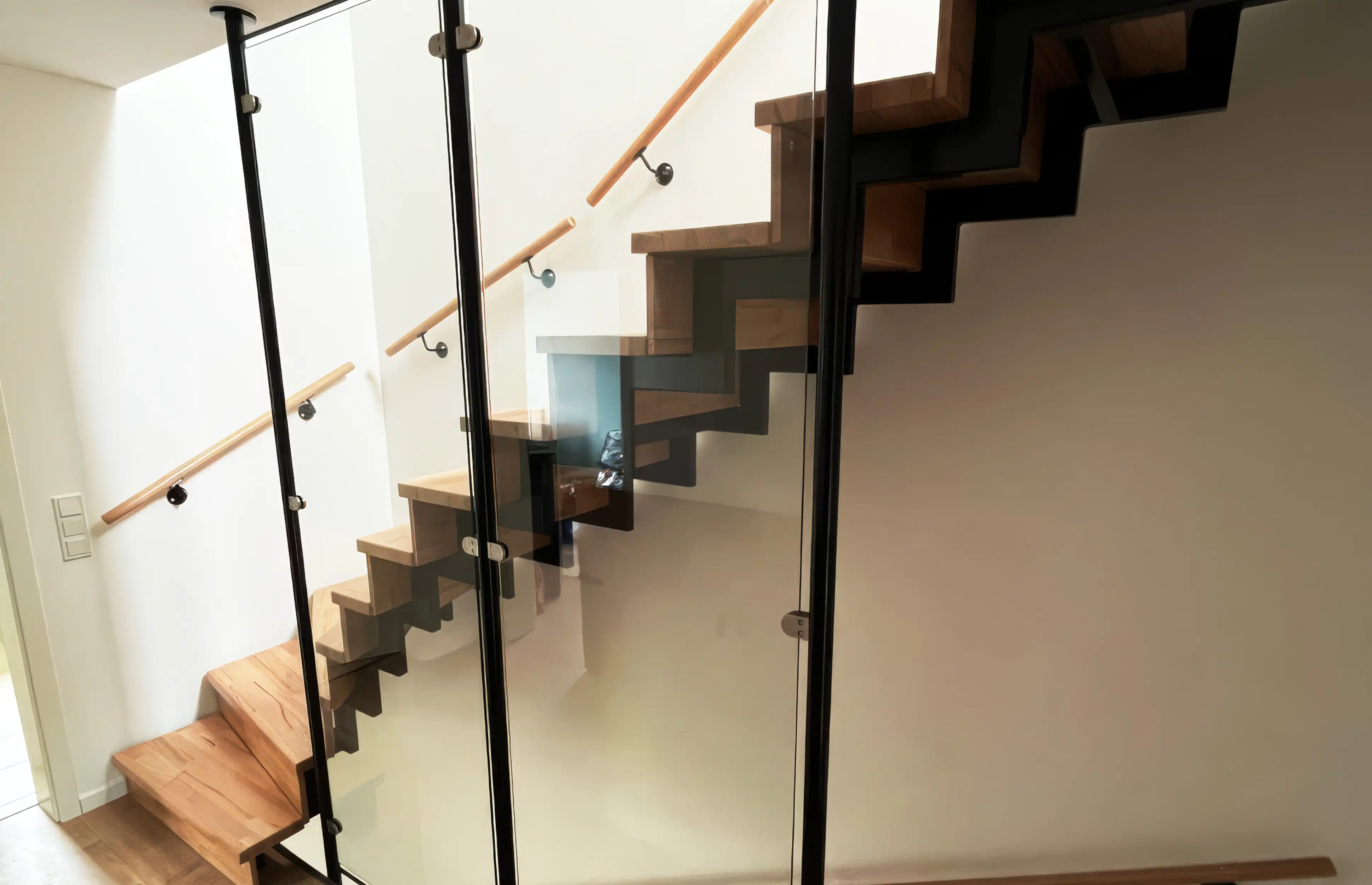 Zweiholmtreppe mit Holzstufen, Setzstufen, dunkler Stahlkonstruktion und Glasgeländer