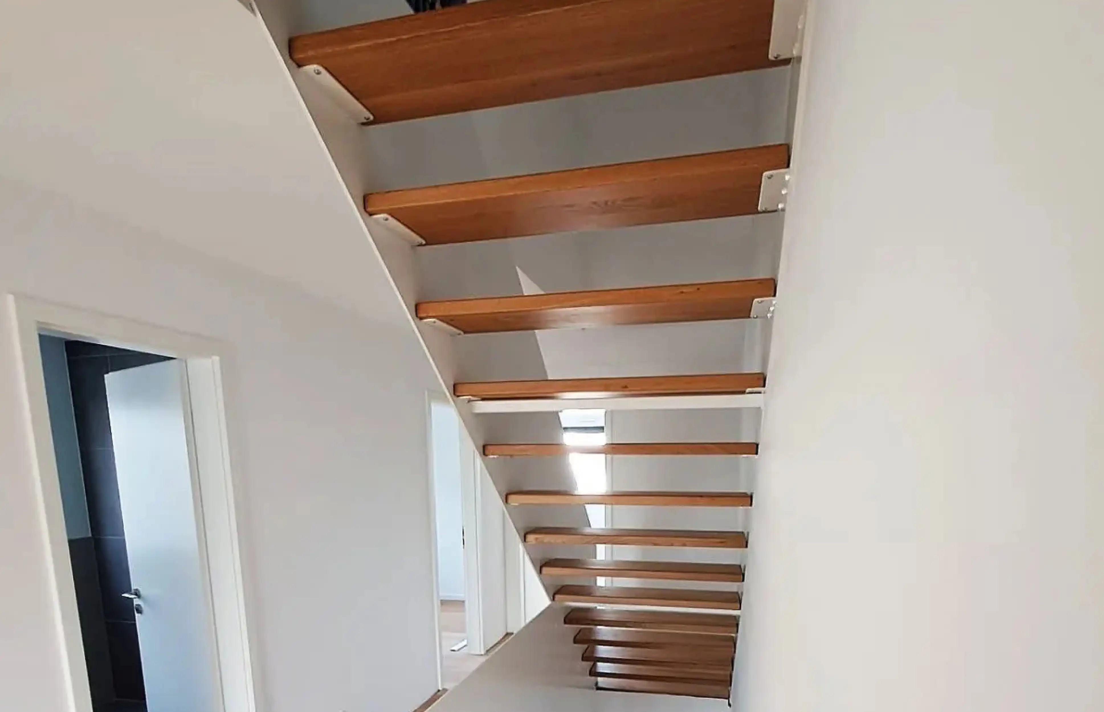 Wangentreppe mit Holzstufen, Setzstufen, Stahlwangen und Glasgeländer von Janßen Metallbau