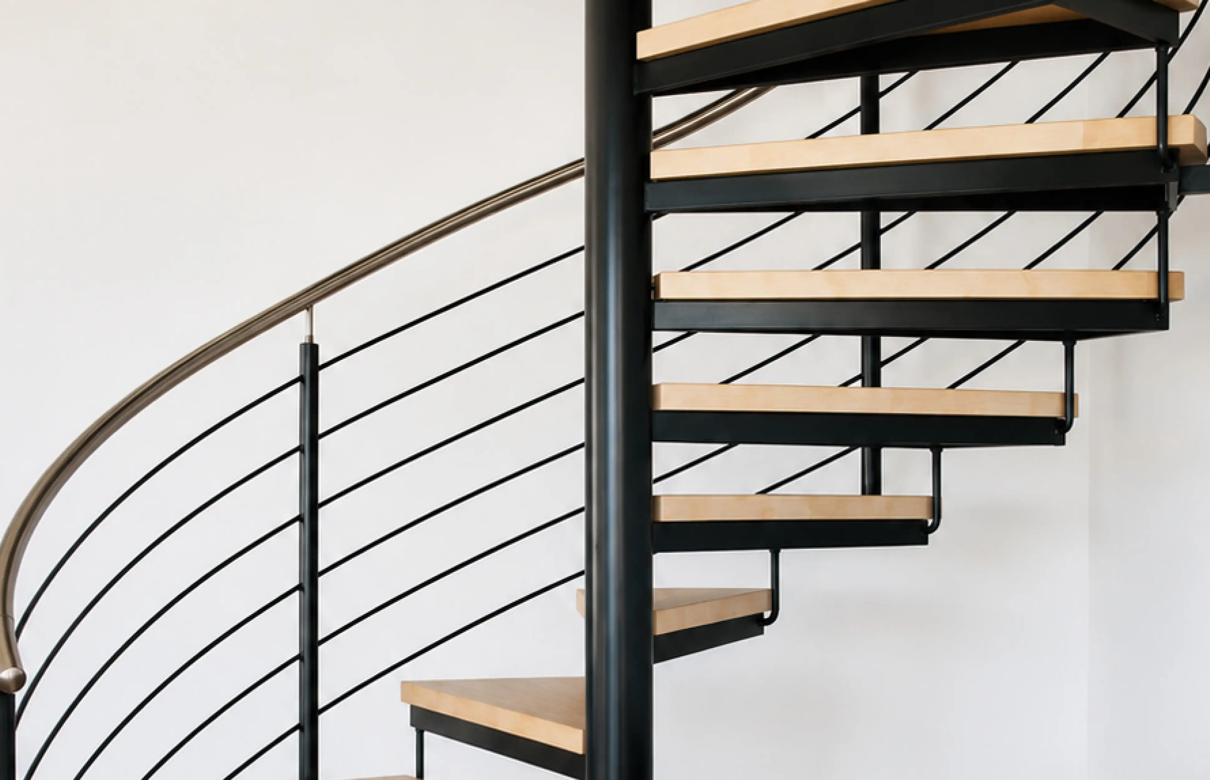 Spindeltreppe auf Maß mit Holzstufen und schwarzer Säule, Stahlgeländer und Edelstahlhandlauf von Janßen