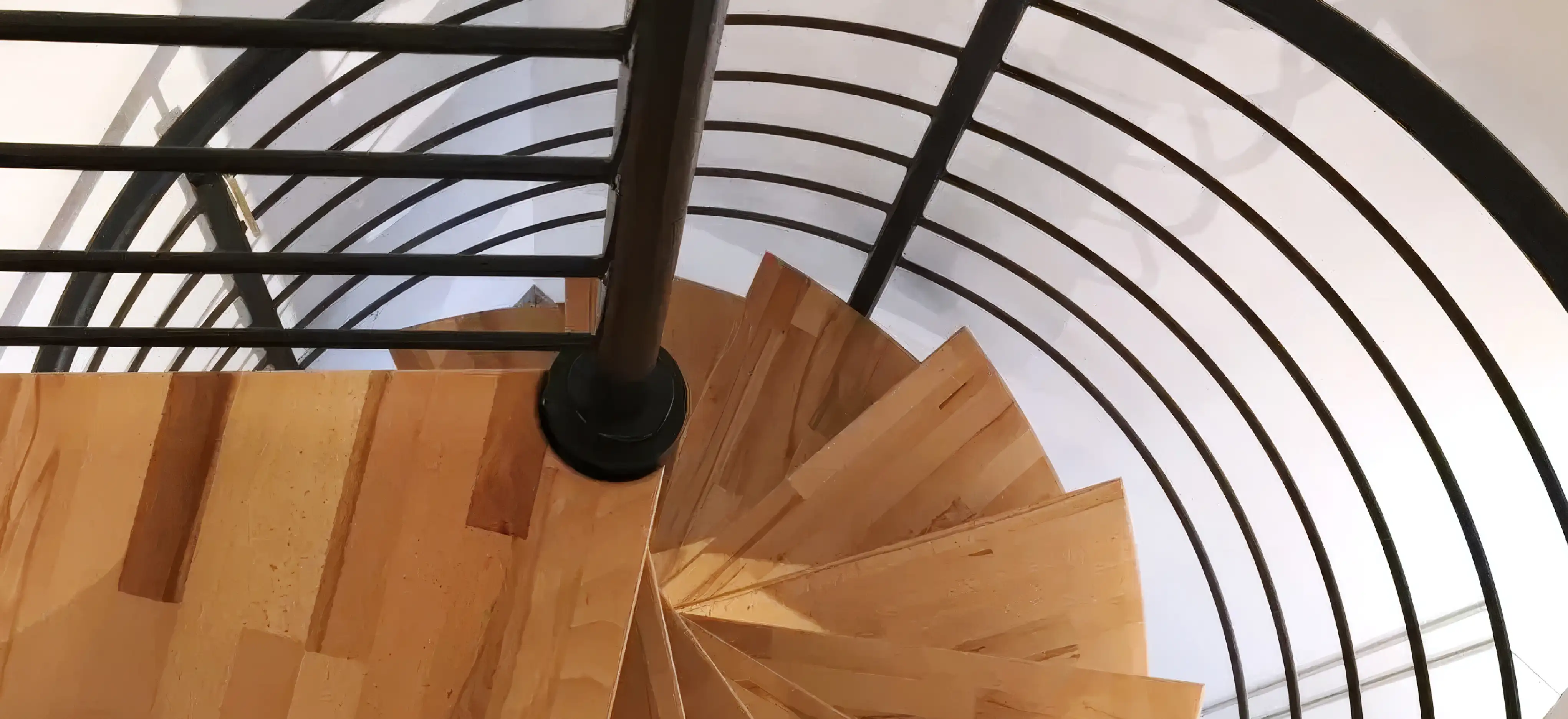Spindeltreppe auf Maß geplant, mit schwarzem Stahlgeländer und Holzstufen aus Buche von Janßen Metallbau
