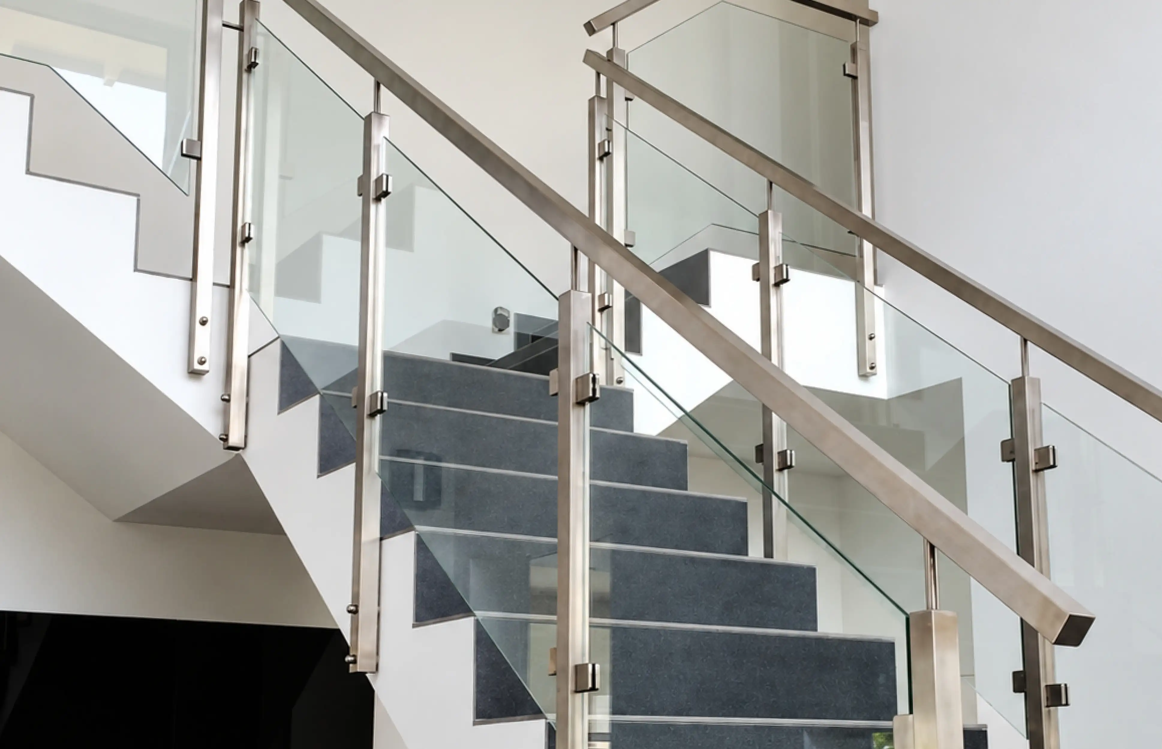 Edelstahlgeländer mit Glas an einer Betontreppe.