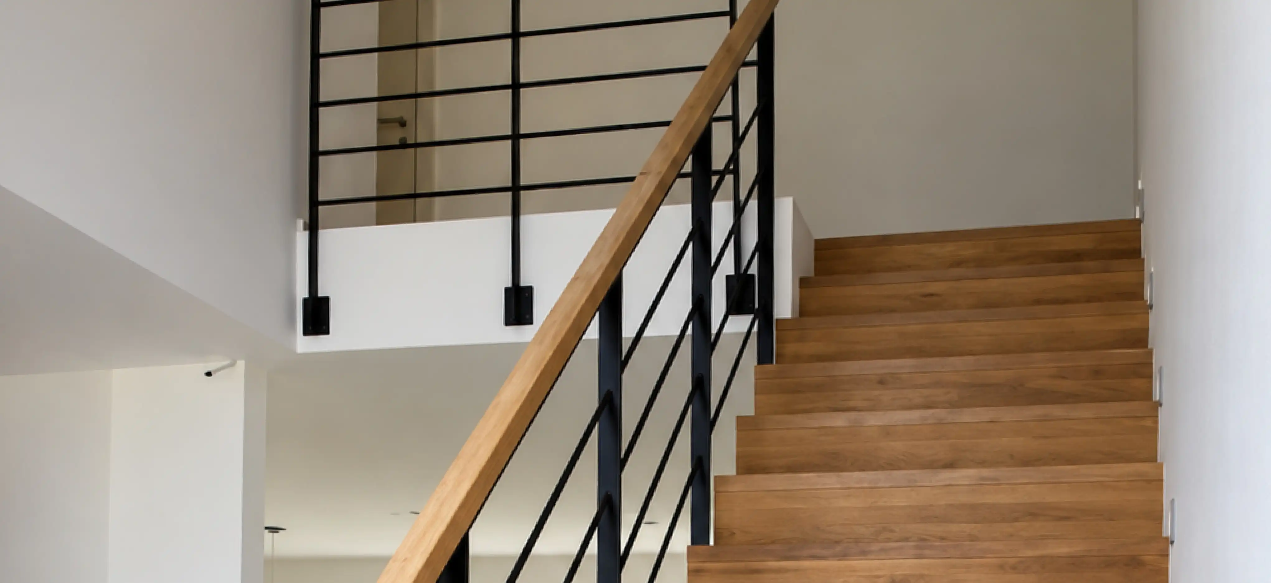 Treppengeländer aus Stahl an einer Betontreppe mit Holzstufen verkleidet und passendem Handlauf aus Holz