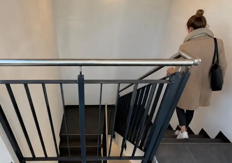 Stahlgeländer mit Edelstahlhandlauf an einer Betontreppe im Treppenhaus