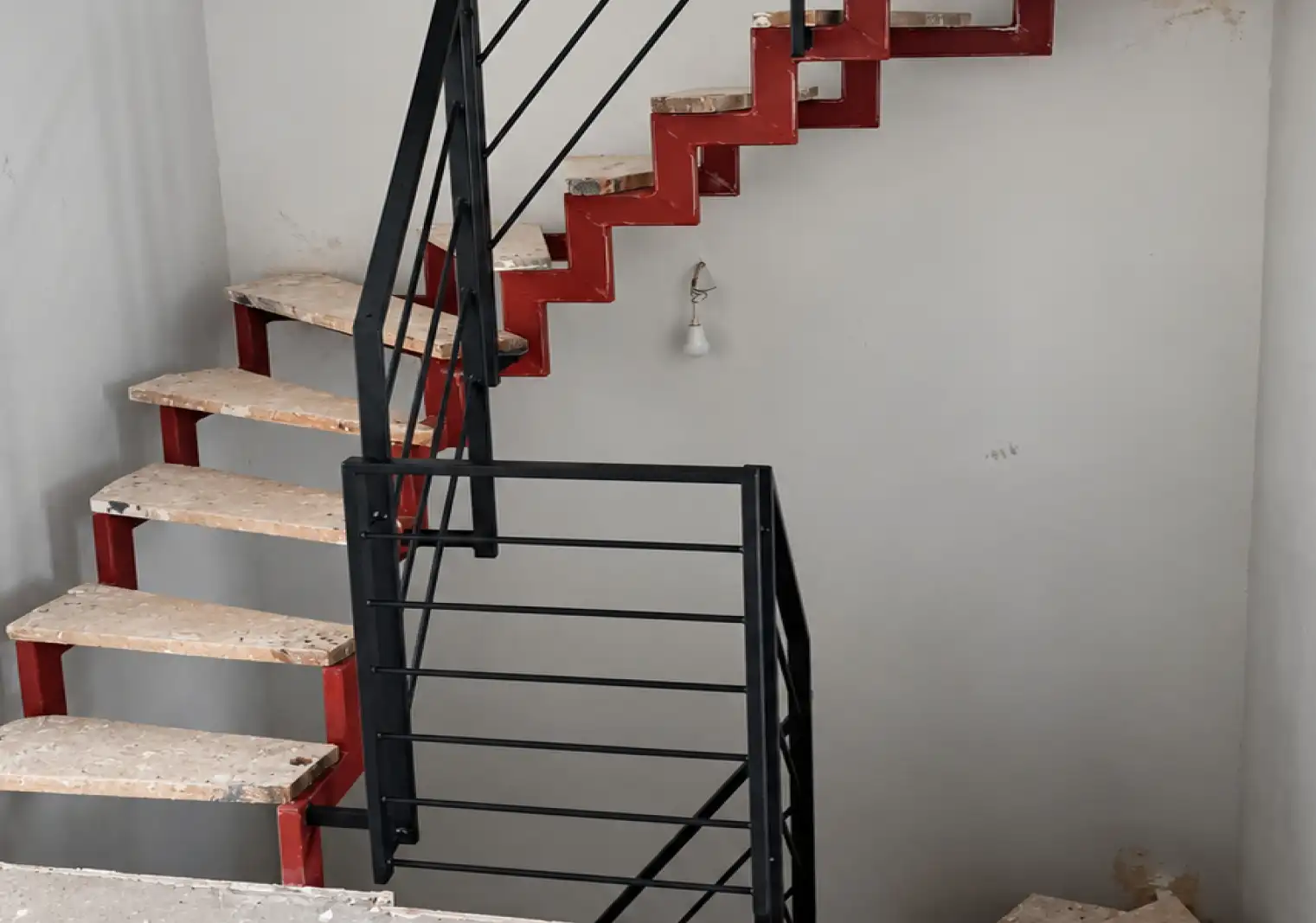 Eine Zweiholmtreppe steht montiert und teilweise in schwarz angestrichen in einem Treppenhaus
