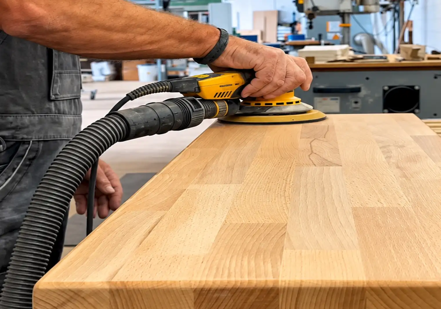 Eine Holzstufe für eine Treppe wird von einem Mitarbeiter geschliffen