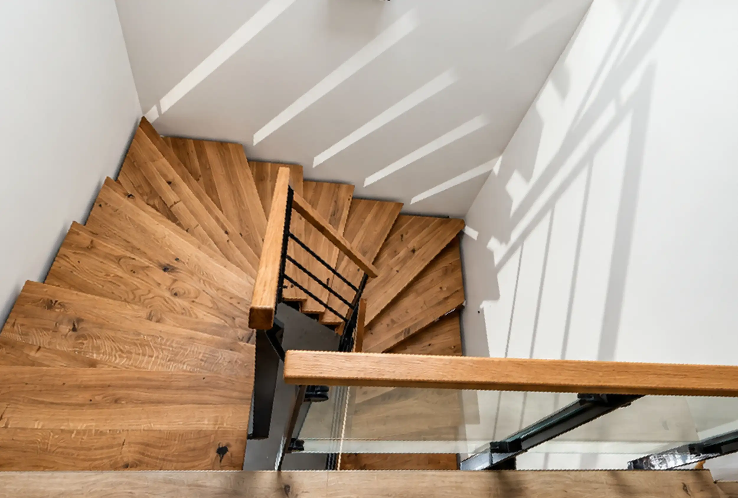 Stahl-Holz-Treppe mit Holzstufen, Stahlgeländer und Glasbrüstung in einem Wohnhaus
